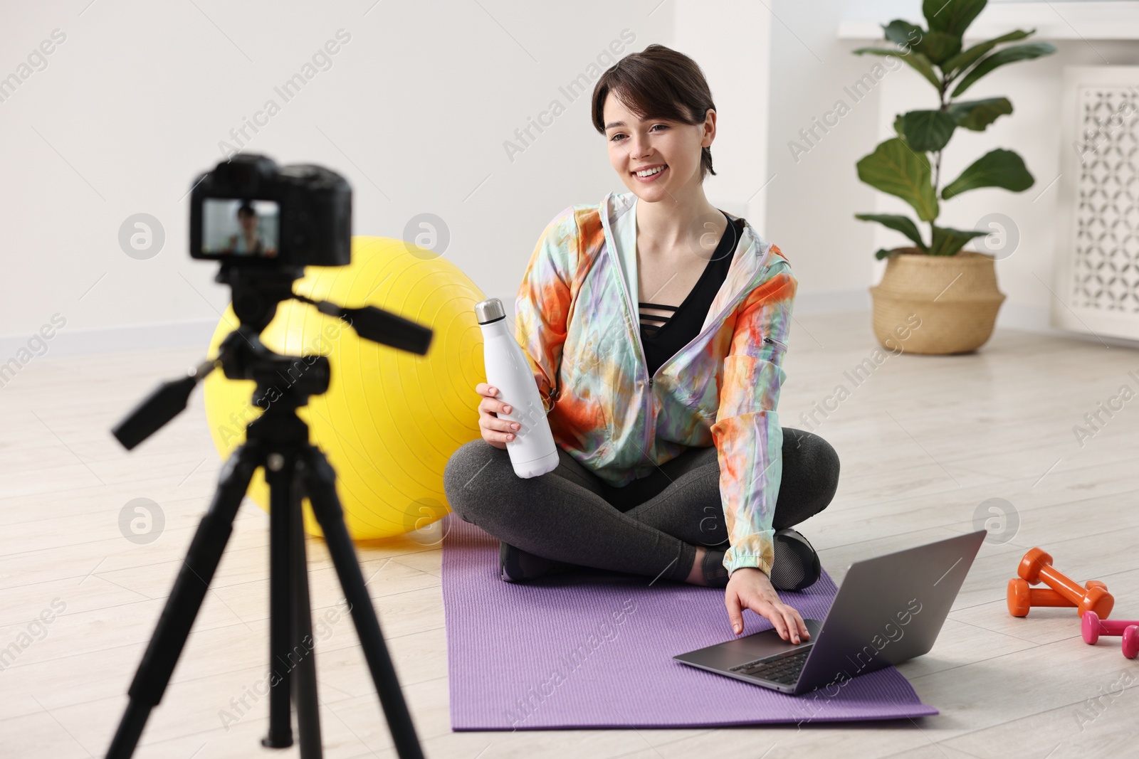 Photo of Happy sports blogger recording fitness lesson with camera at home