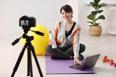 Happy sports blogger recording fitness lesson with camera at home