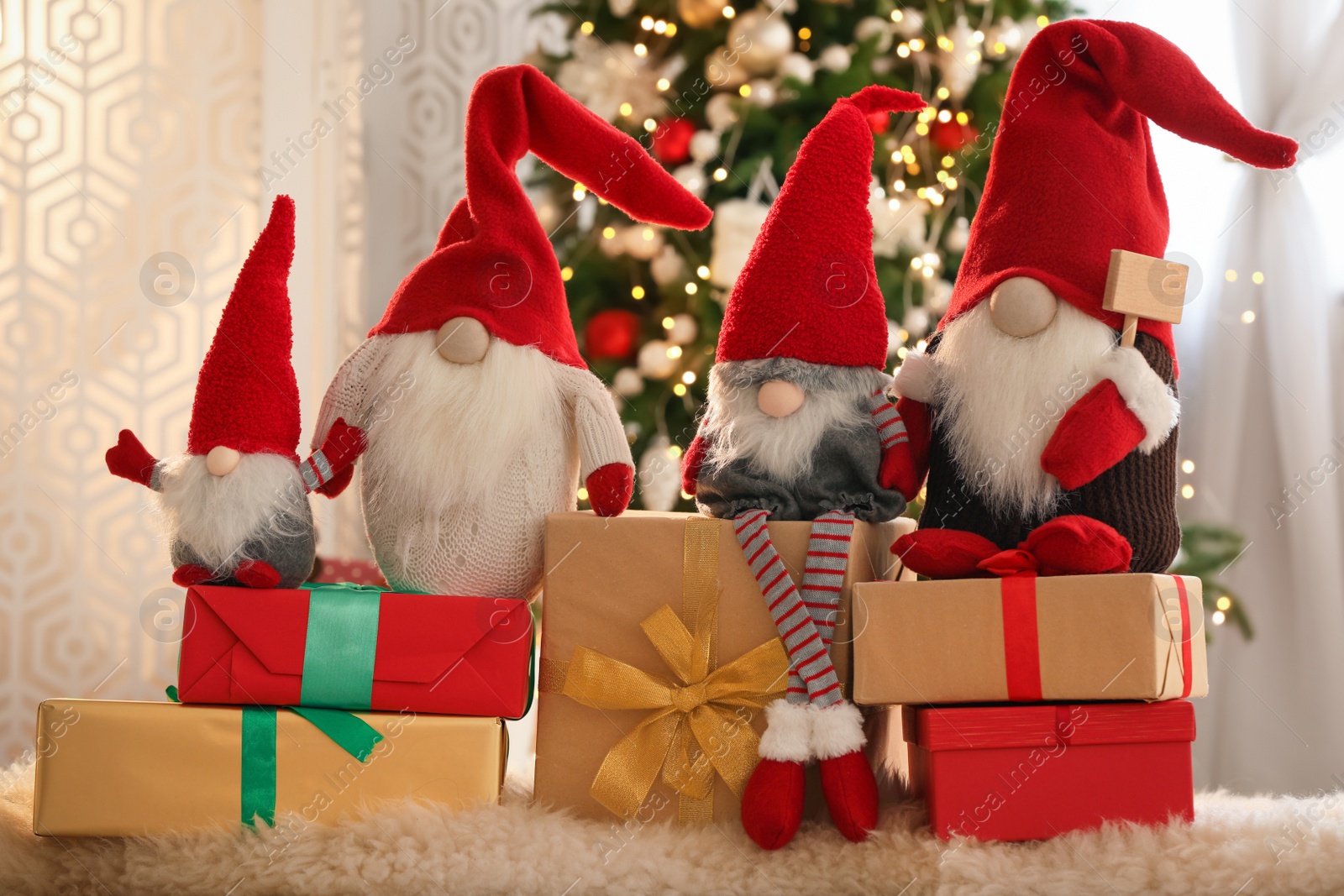 Photo of Cute Christmas gnomes and gift boxes on carpet in room