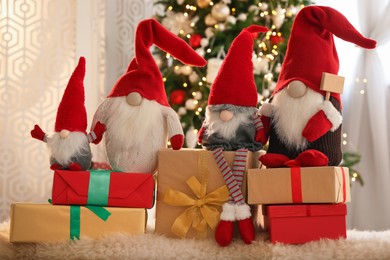 Photo of Cute Christmas gnomes and gift boxes on carpet in room