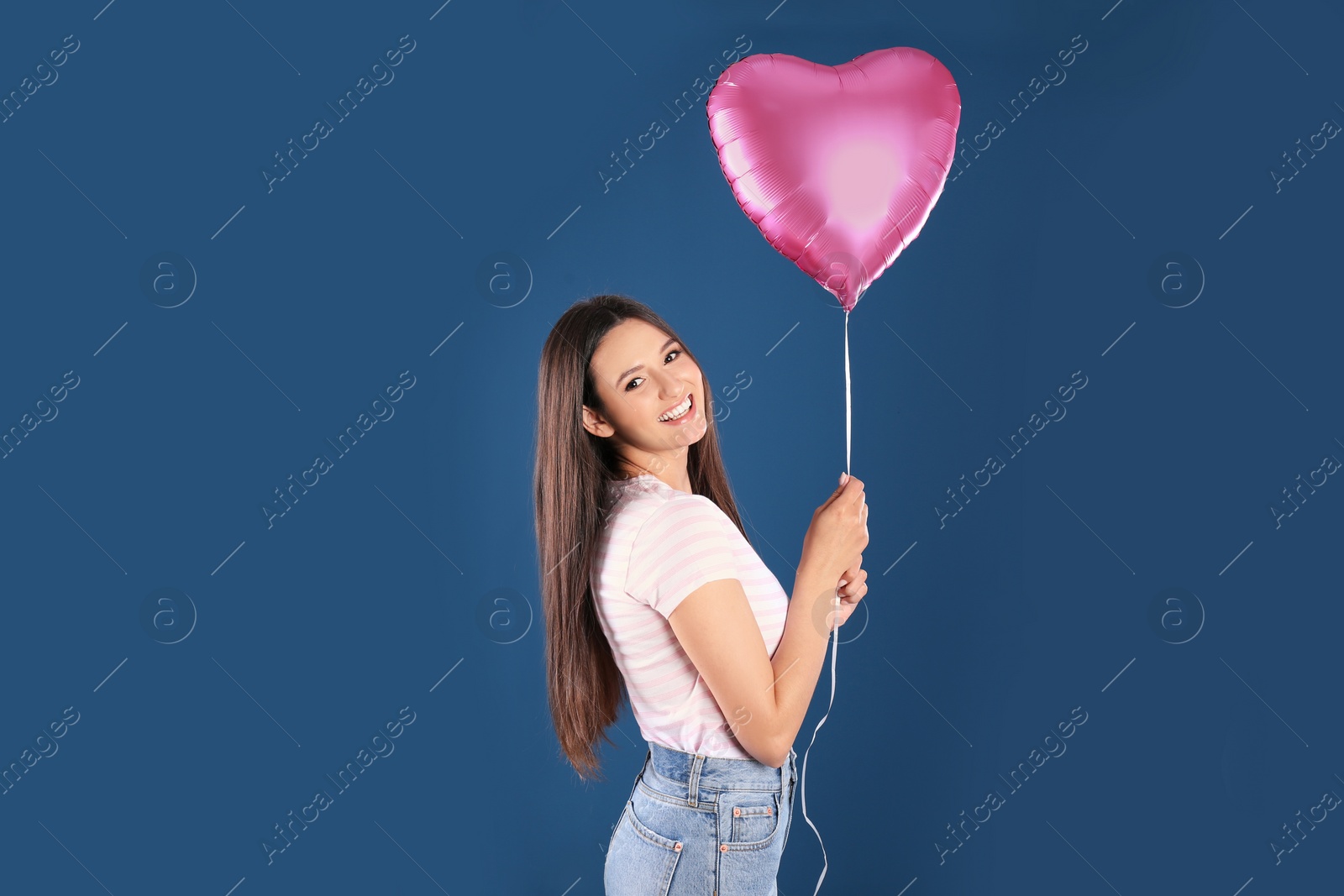 Photo of Portrait of young woman with heart shaped balloon on color background