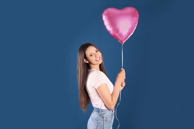 Photo of Portrait of young woman with heart shaped balloon on color background