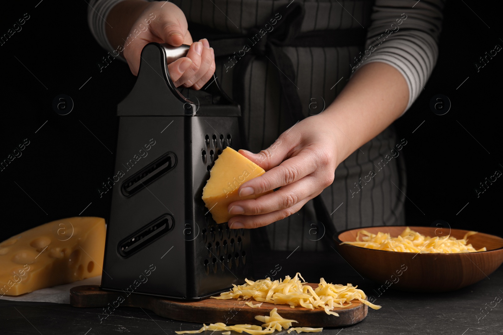 Photo of Woman grating fresh cheese at black table, closeup