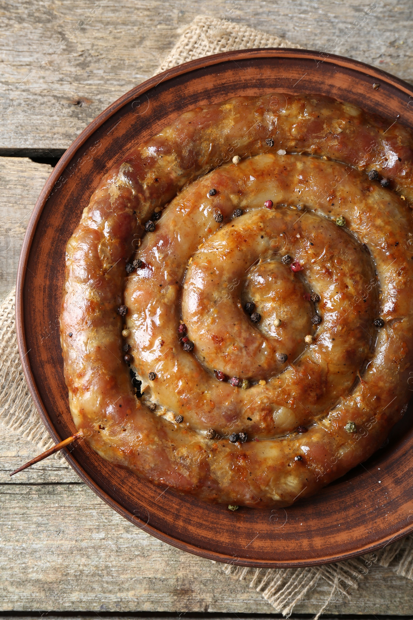 Photo of Plate with tasty homemade sausages on wooden table, top view