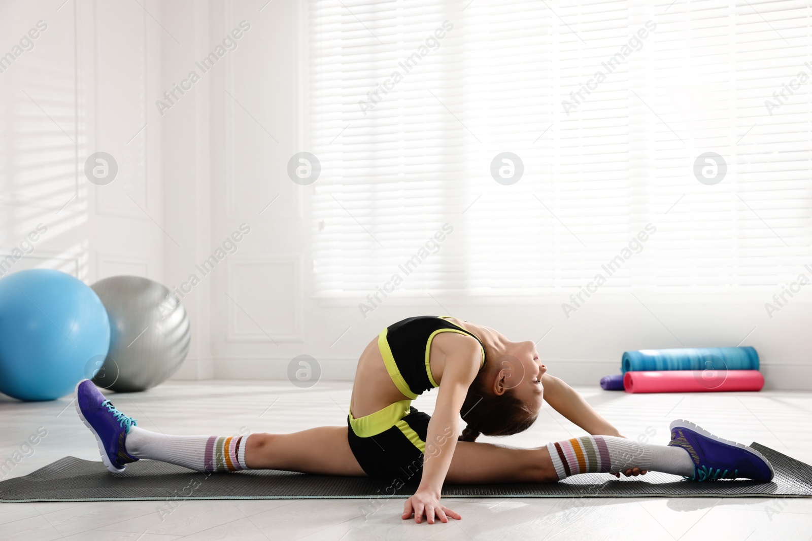 Photo of Cute little girl doing gymnastic exercise indoors