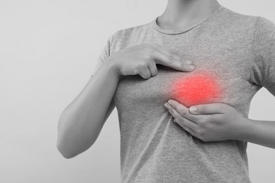 Woman doing breast self-examination on grey background, closeup. Color accent effect