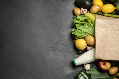 Photo of Paper bag with fresh vegetables and fruits on grey background, flat lay. Space for text