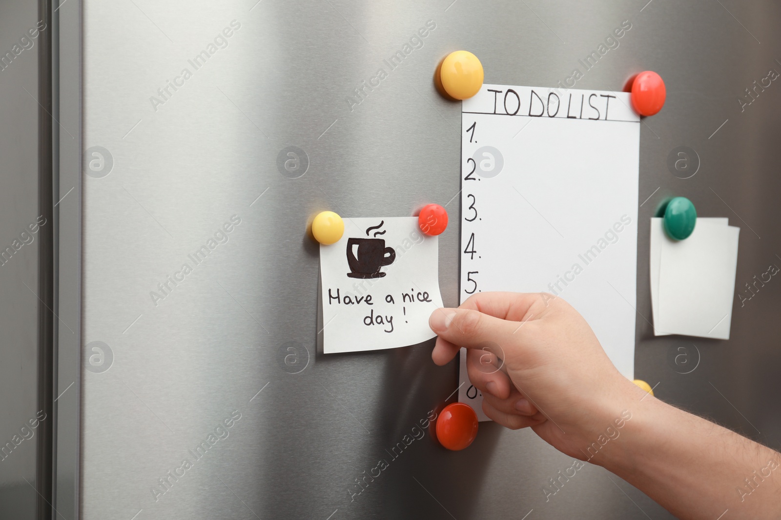 Photo of Man putting paper sheet on refrigerator door, closeup