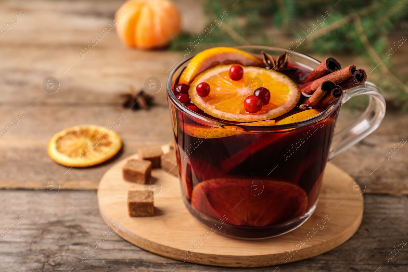 Photo of Glass cup with tasty mulled wine on wooden table