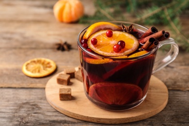 Glass cup with tasty mulled wine on wooden table