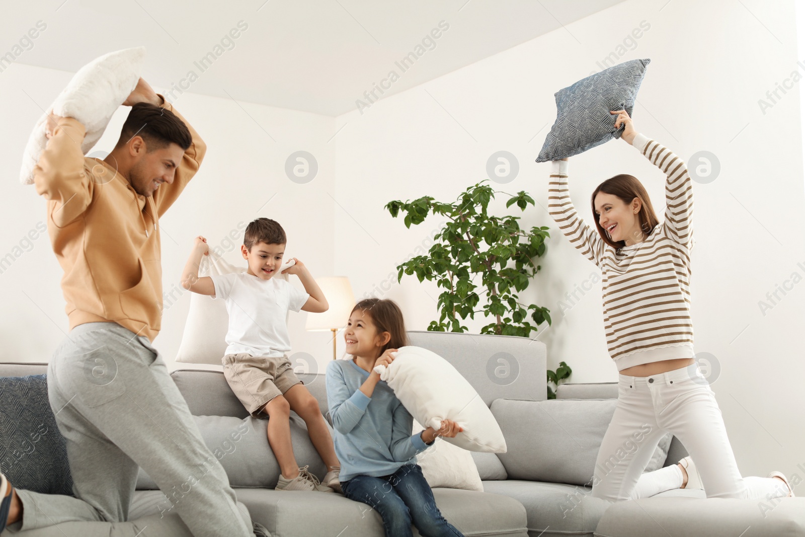 Photo of Happy family having pillow fight in living room