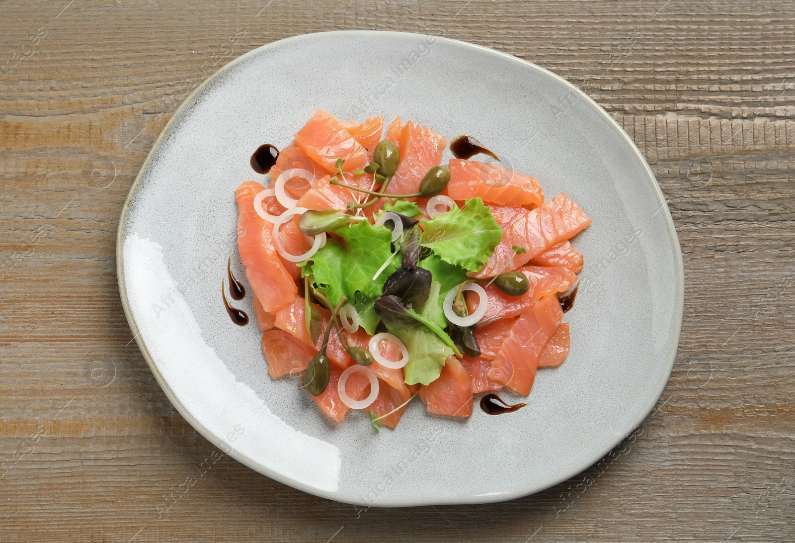 Photo of Delicious salmon carpaccio served on wooden table, top view