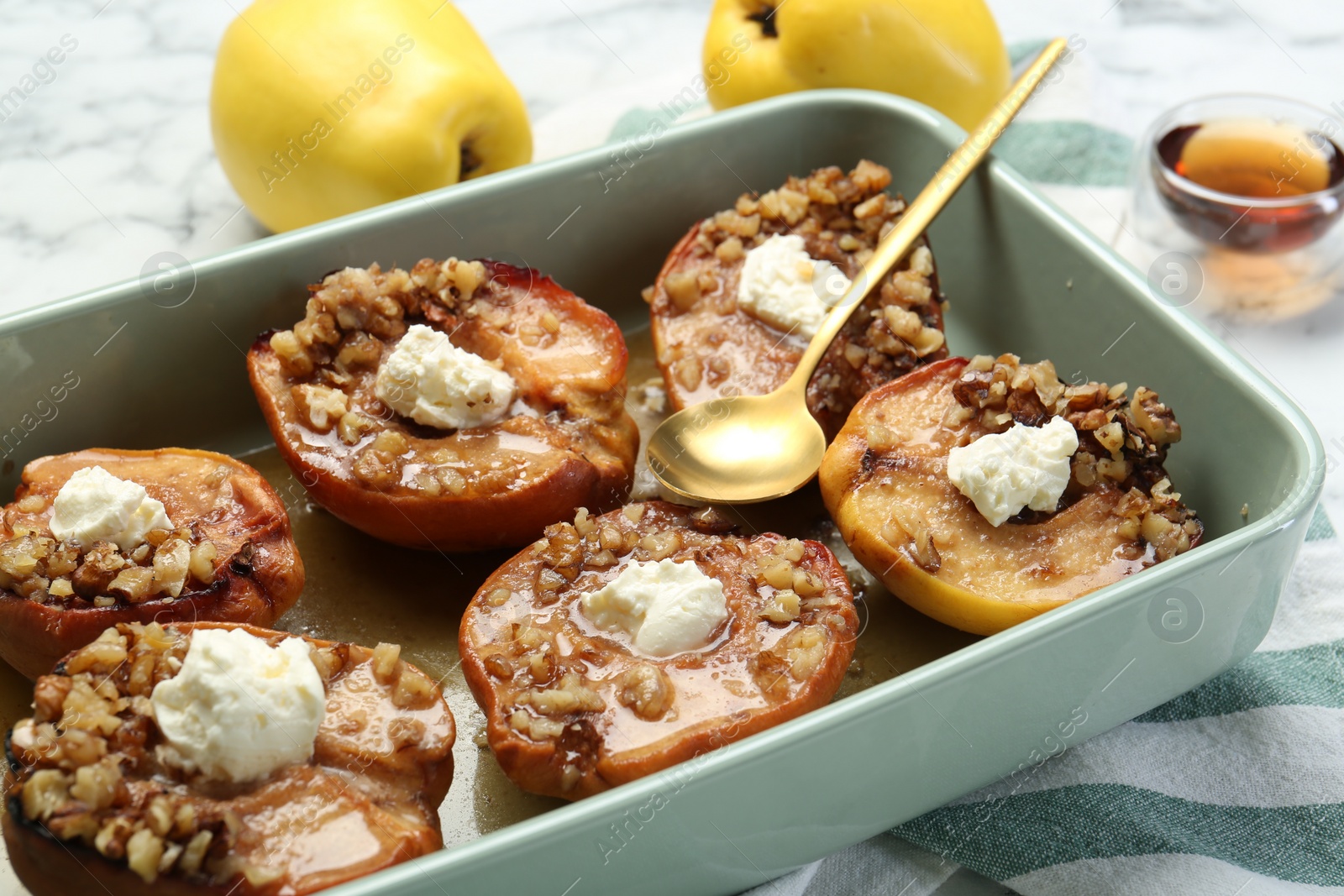 Photo of Tasty baked quinces with nuts and cream cheese in dish on table, closeup