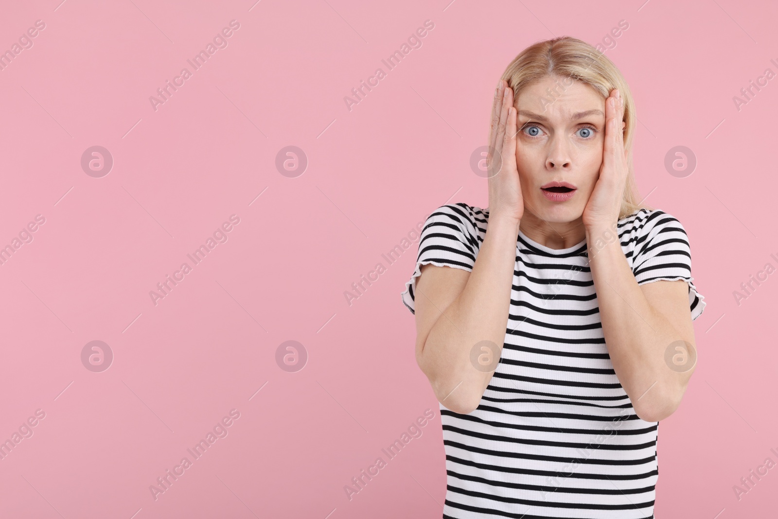 Photo of Portrait of surprised woman on pink background, space for text