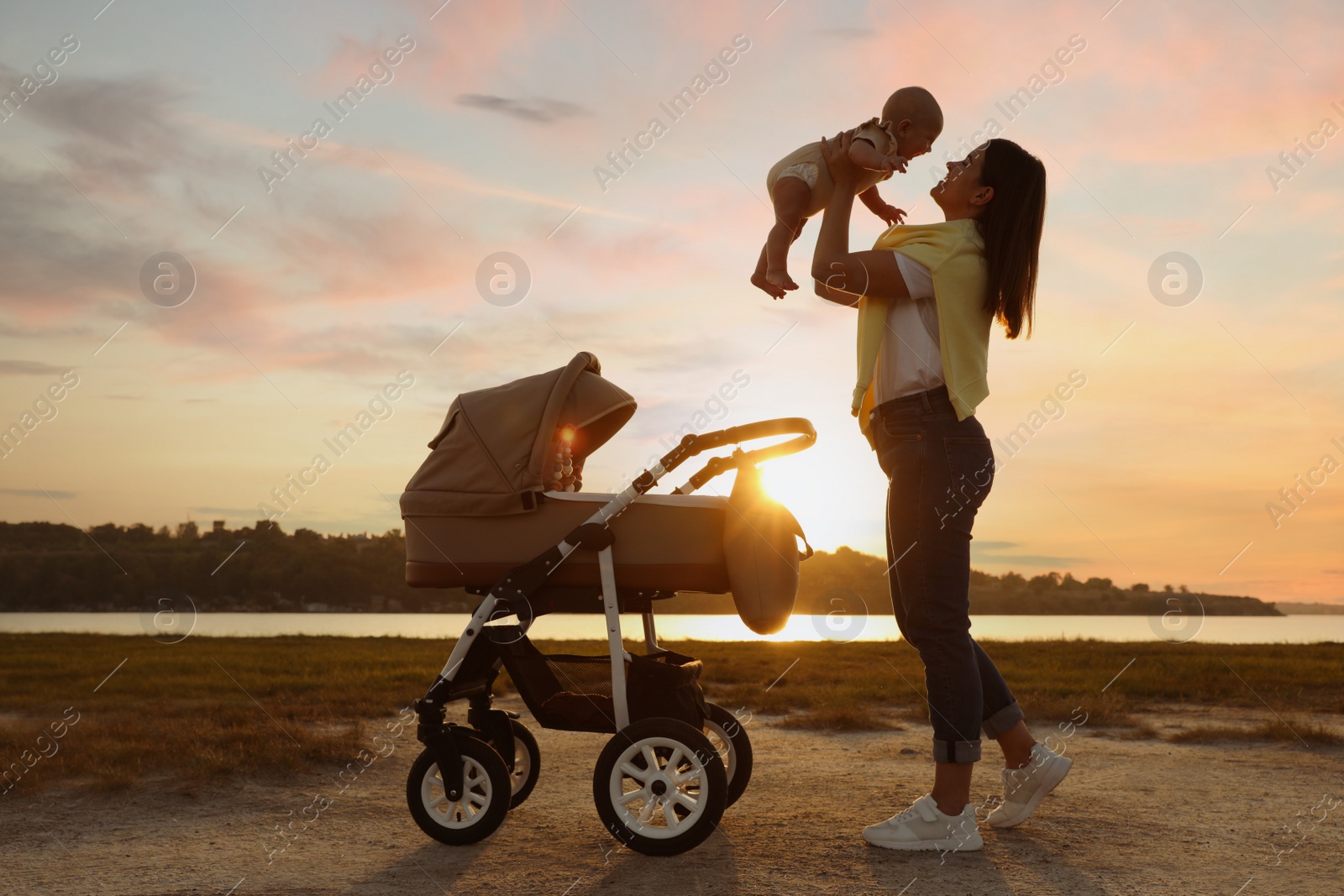 Photo of Happy mother with baby near river at sunset