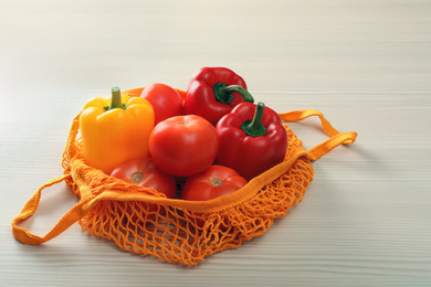 Net bag with vegetables on wooden table