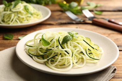 Tasty zucchini pasta with basil served on wooden table