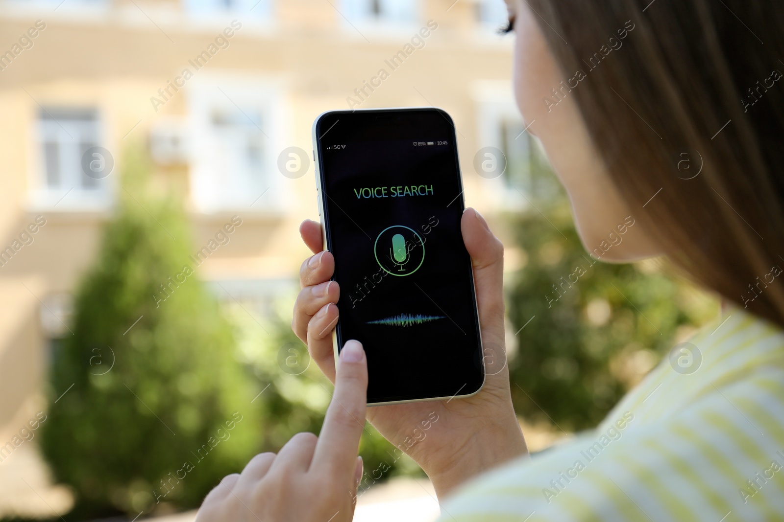 Photo of Woman using voice search on smartphone outdoors, closeup