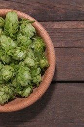 Bowl of fresh green hops on wooden table, top view