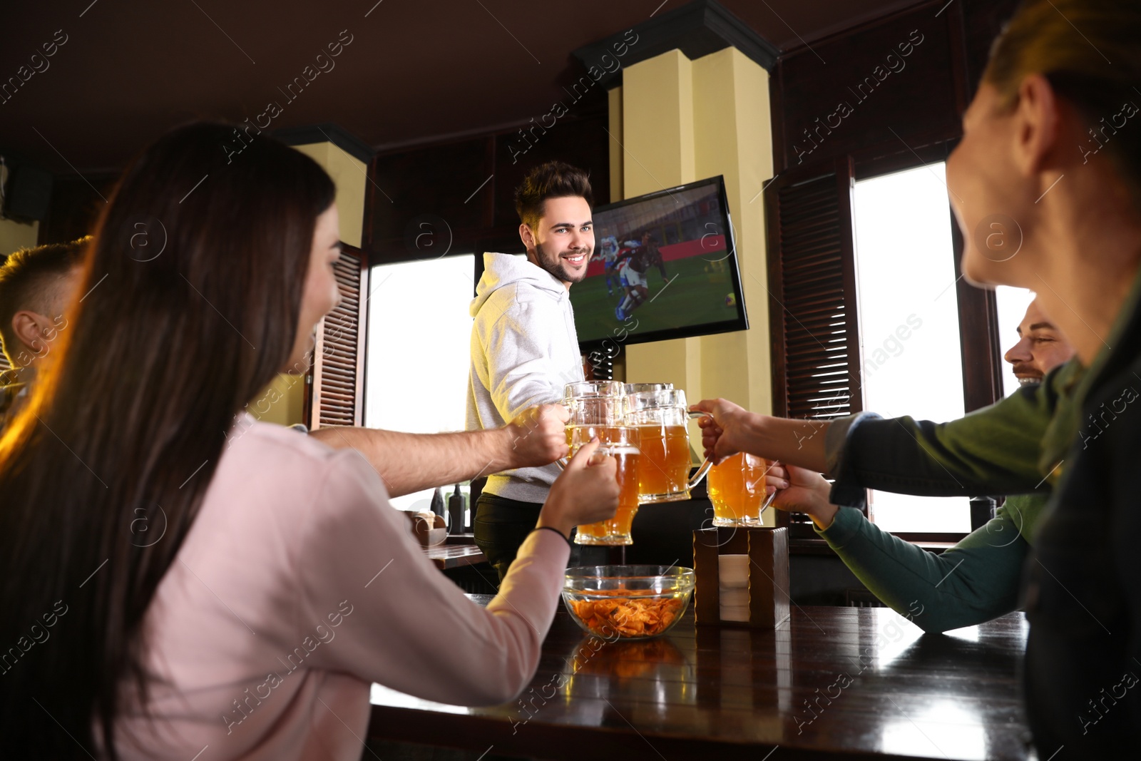 Photo of Group of friends celebrating victory of favorite football team in sport bar