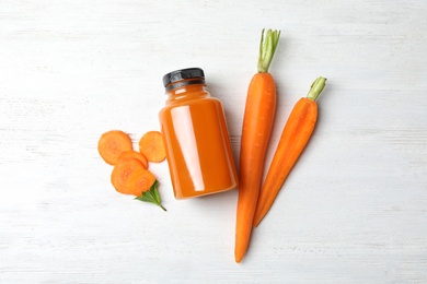 Flat lay composition with carrots and juice on white wooden table