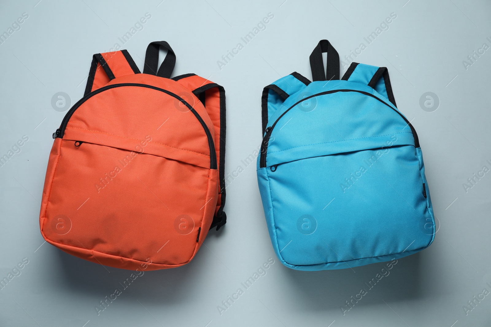 Photo of Stylish backpacks on light grey background, flat lay