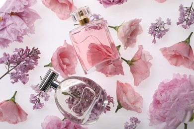 Photo of Luxury perfumes on spring floral decor, top view