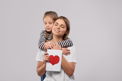 Photo of Little daughter congratulating her mom with postcard on white background, space for text. Happy Mother's Day