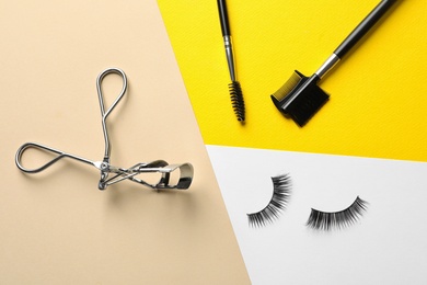 Photo of False eyelashes, curler and brushes on color background, flat lay