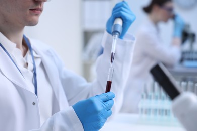 Scientist dripping sample into test tube in laboratory, closeup