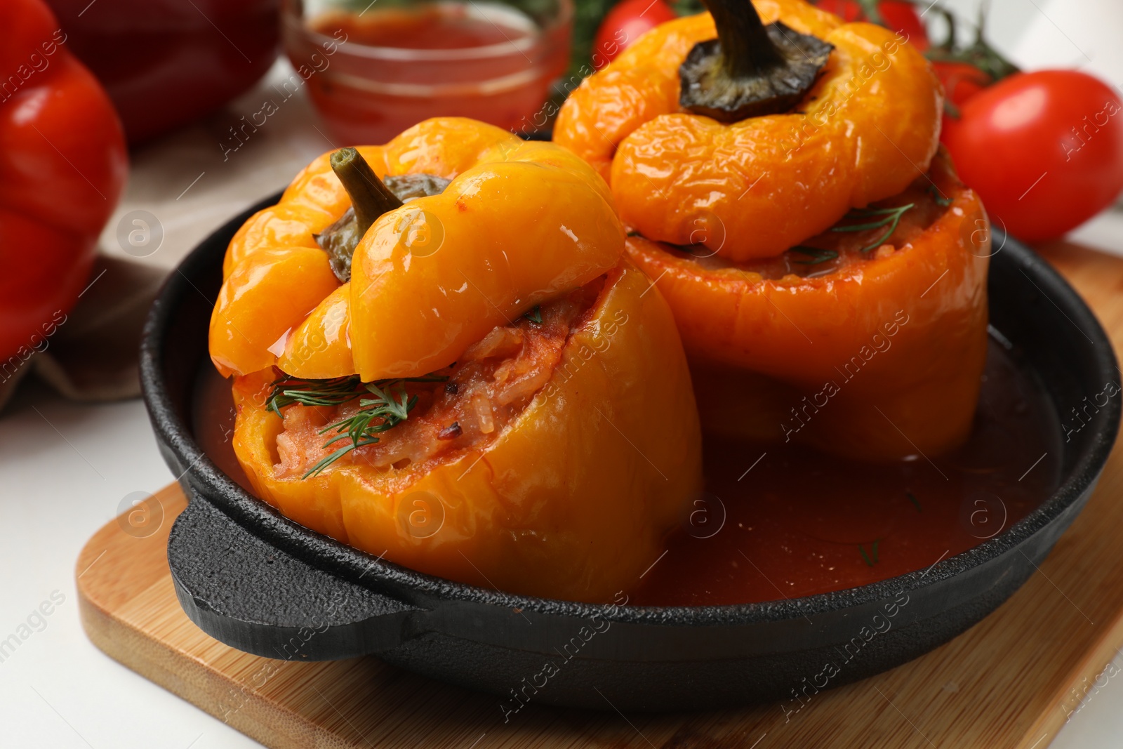 Photo of Tasty stuffed peppers in pan on light table, closeup