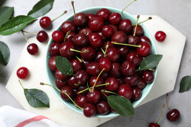 Photo of Sweet juicy cherries and leaves on grey table, flat lay