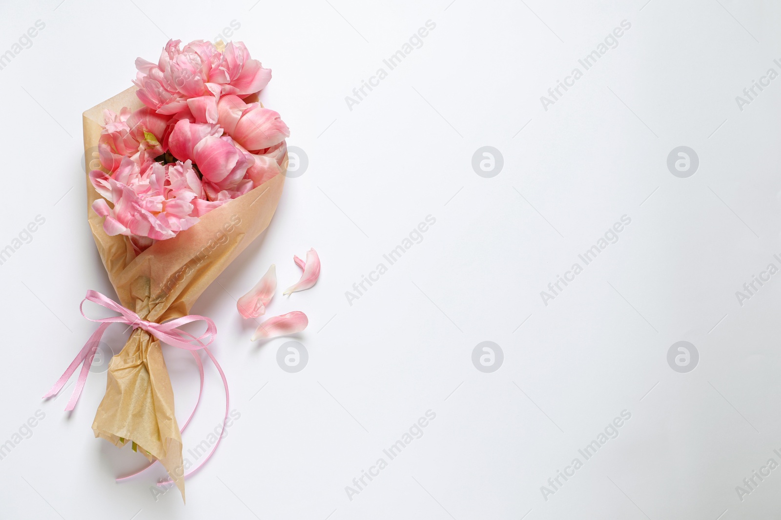 Photo of Beautiful bouquet of pink peonies wrapped in paper on white background, top view