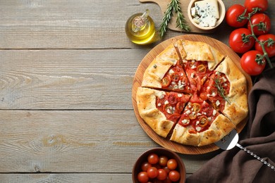 Photo of Flat lay composition of tasty galette with tomato, rosemary and cheese (Caprese galette) on wooden table. Space for text