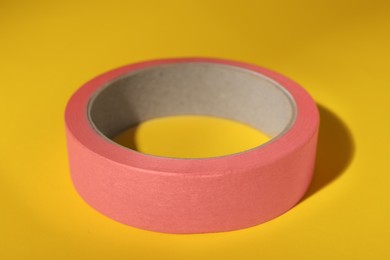 Photo of Roll of pink adhesive tape on yellow background