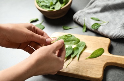 Photo of Woman with fresh green healthy spinach at grey table, closeup