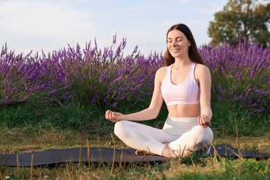 Photo of Smiling woman practicing yoga near blooming lavender outdoors. Space for text