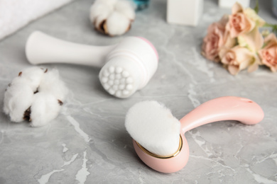 Photo of Modern face cleansing brush on light grey marble table. Cosmetic accessory