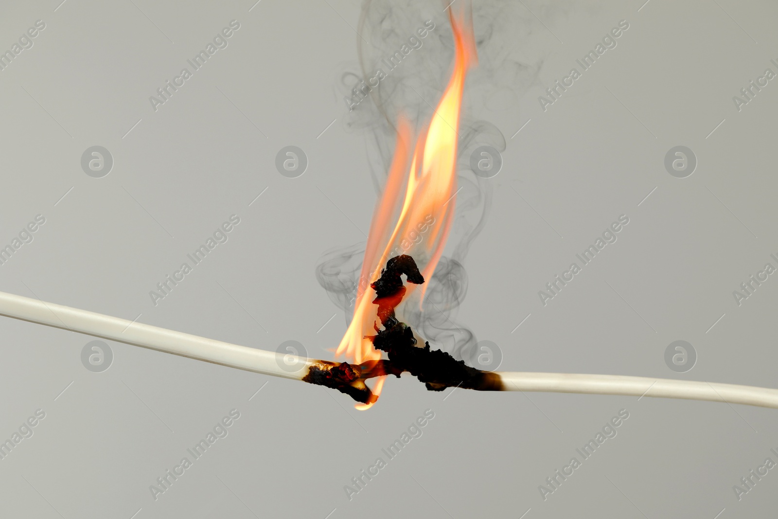 Image of Electrical wire burning on light background, closeup