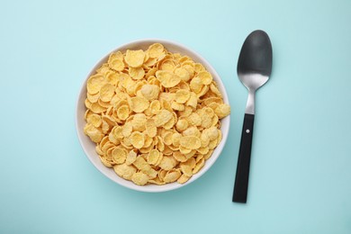 Breakfast cereal. Tasty corn flakes in bowl on light blue table, flat lay