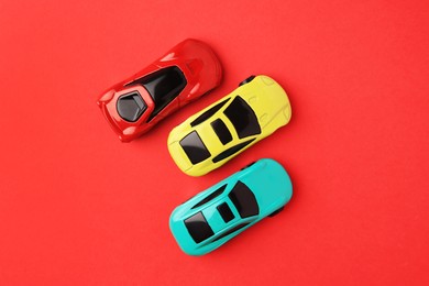 Photo of Different bright cars on red background, flat lay