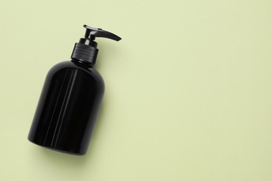 Photo of Bottle of face cleansing product on olive background, top view. Space for text
