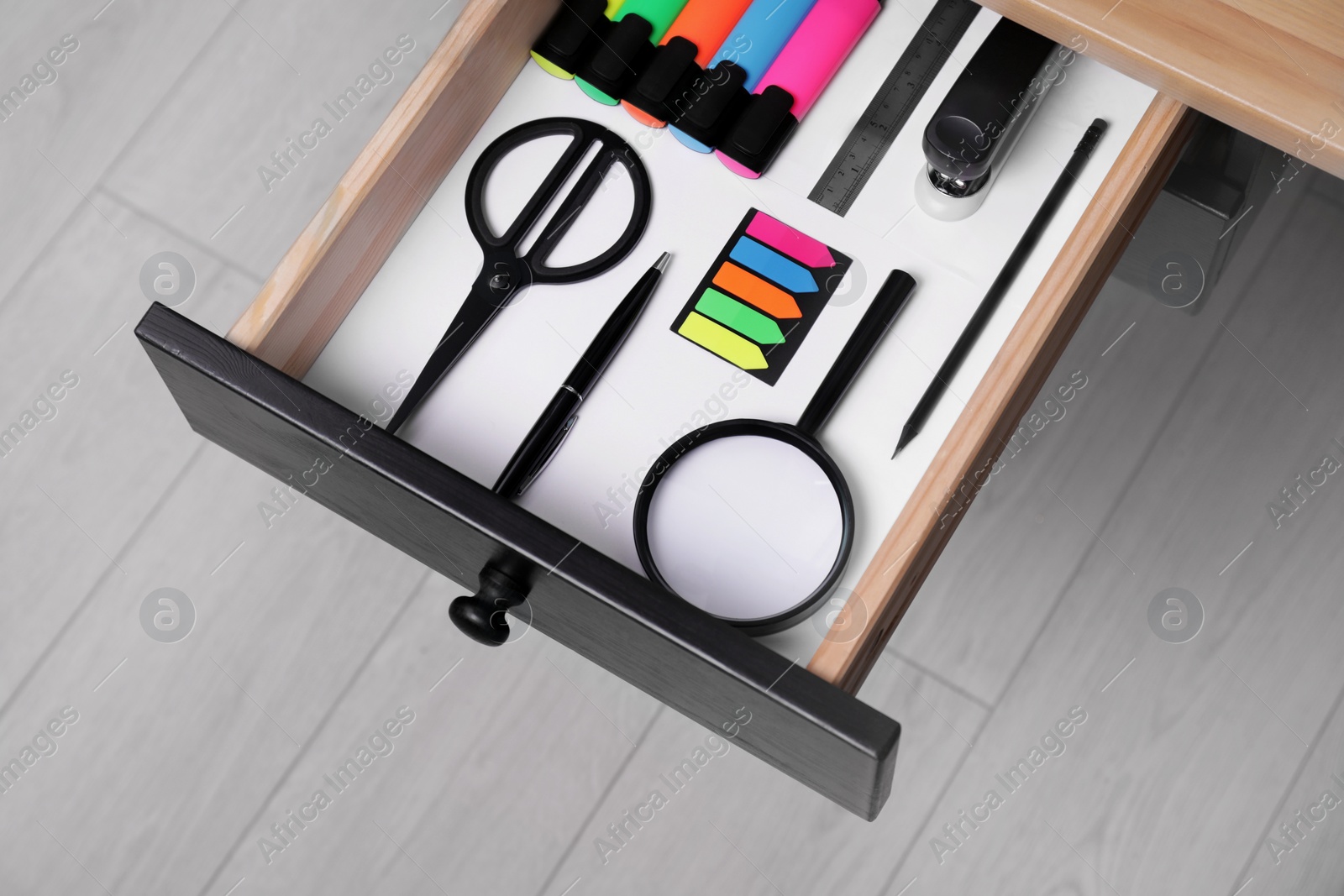 Photo of Office supplies in open desk drawer, above view