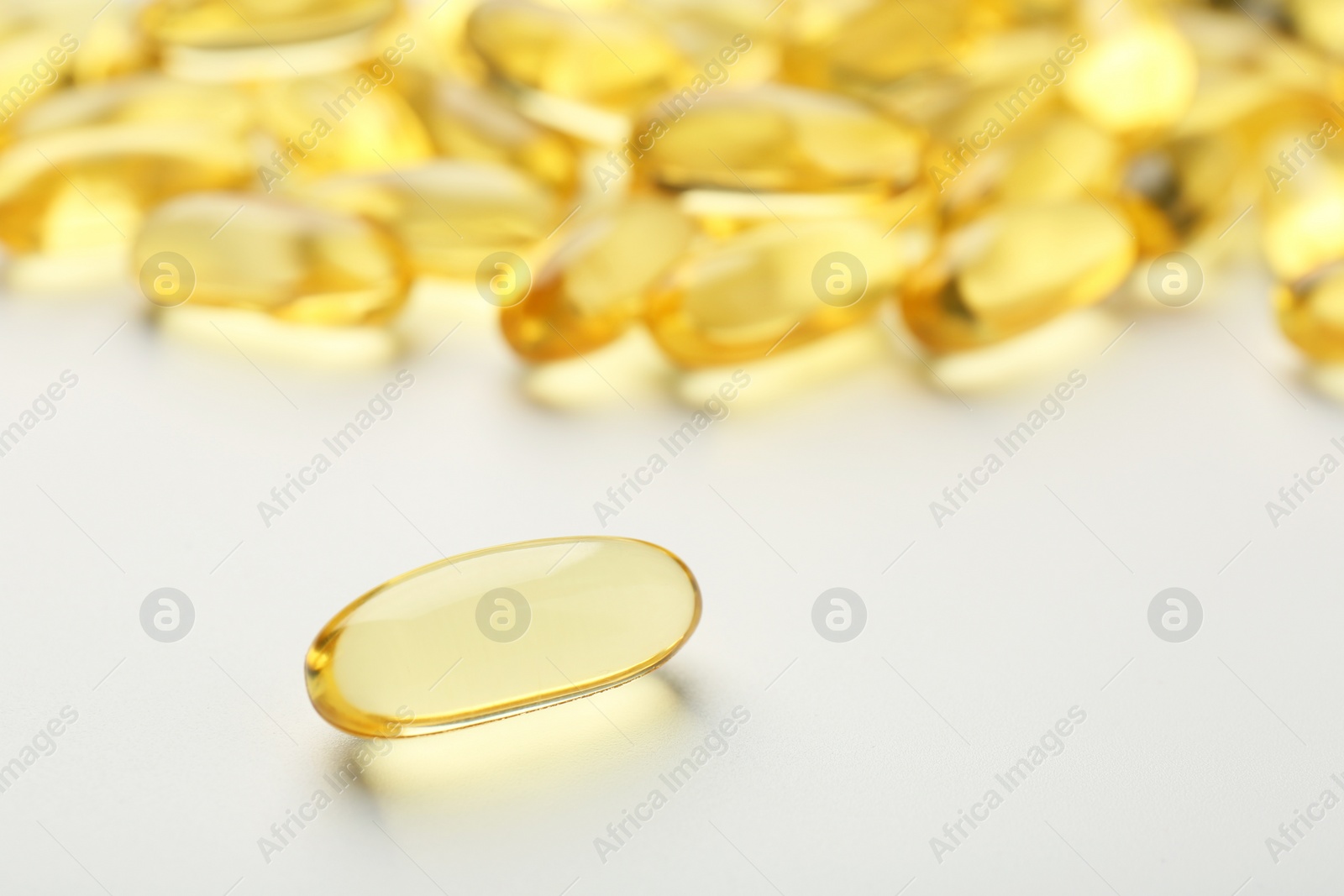 Photo of Yellow vitamin capsules on white background, closeup