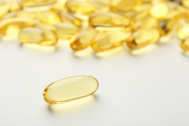 Yellow vitamin capsules on white background, closeup