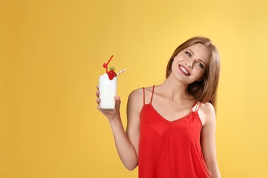 Photo of Young woman with glass of delicious milk shake on color background