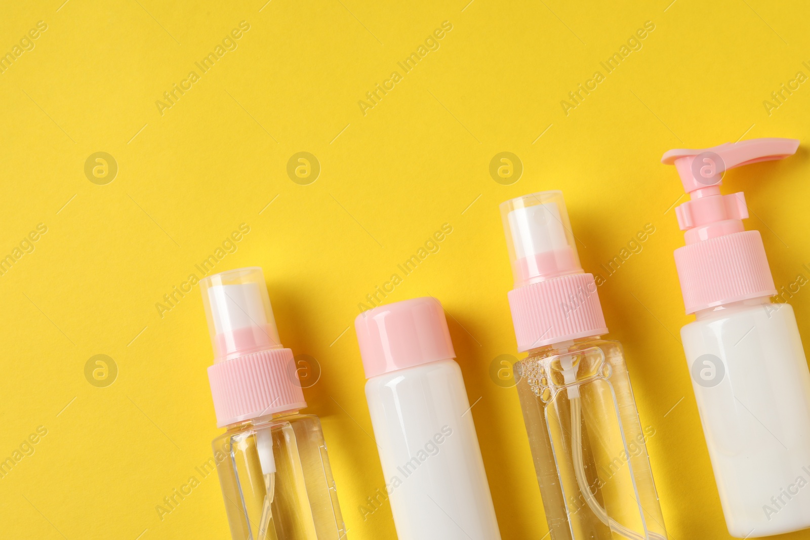 Photo of Cosmetic travel kit on yellow background, flat lay. Space for text