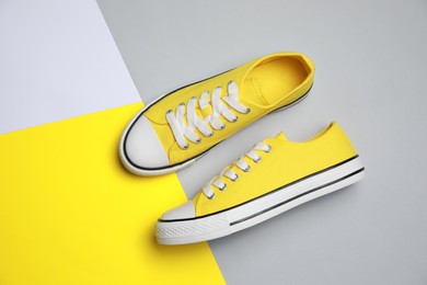 Photo of Pair of yellow classic old school sneakers on color background, flat lay