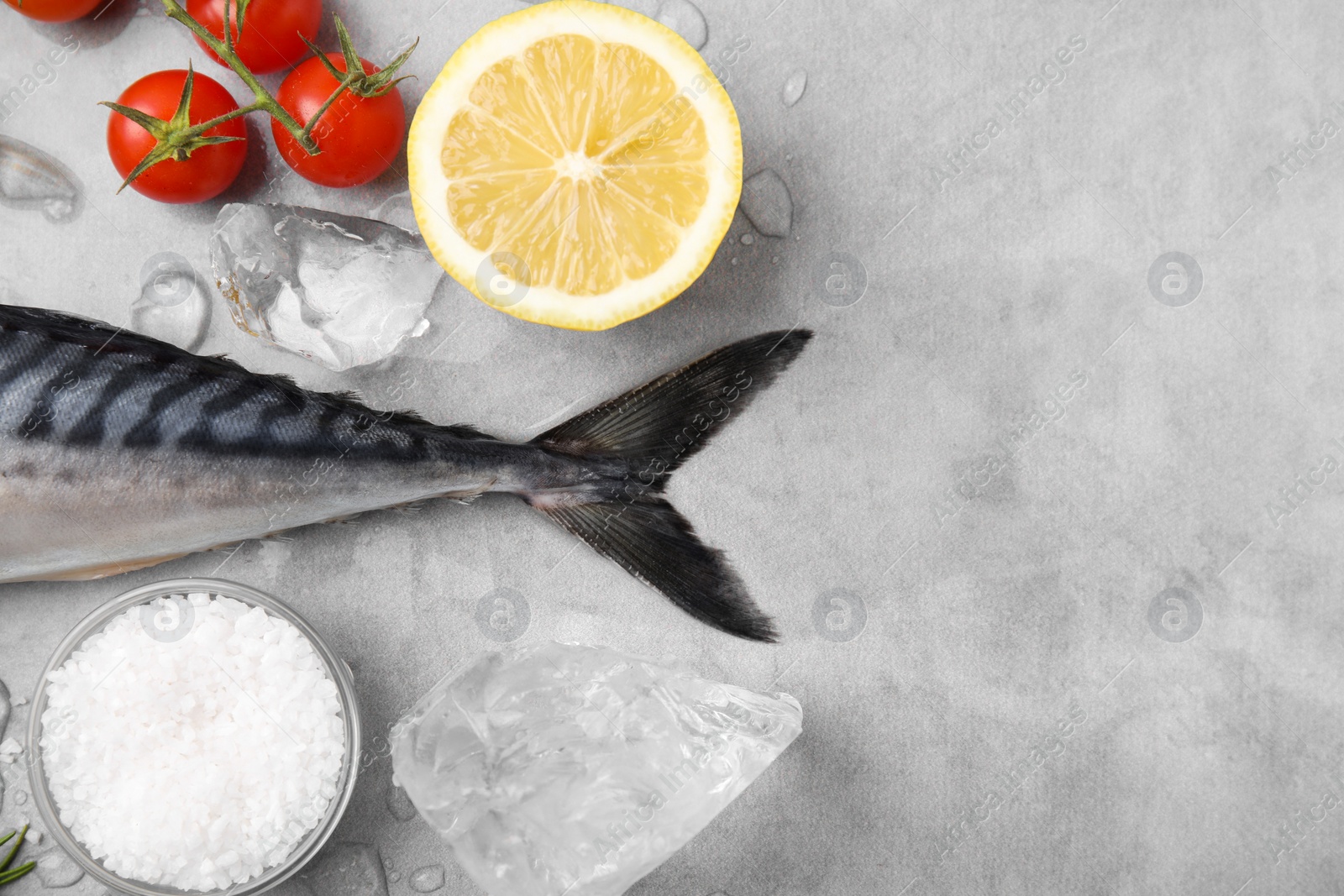 Photo of Raw mackerel, tomatoes and lemon on light gray table, flat lay. Space for text