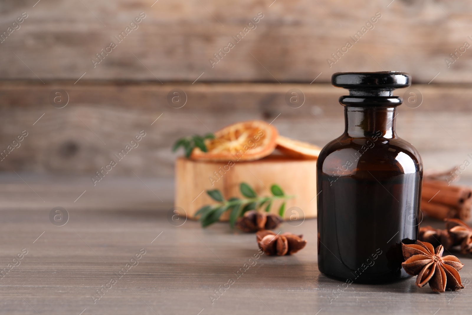 Photo of Anise essential oil and spice on wooden table. Space for text